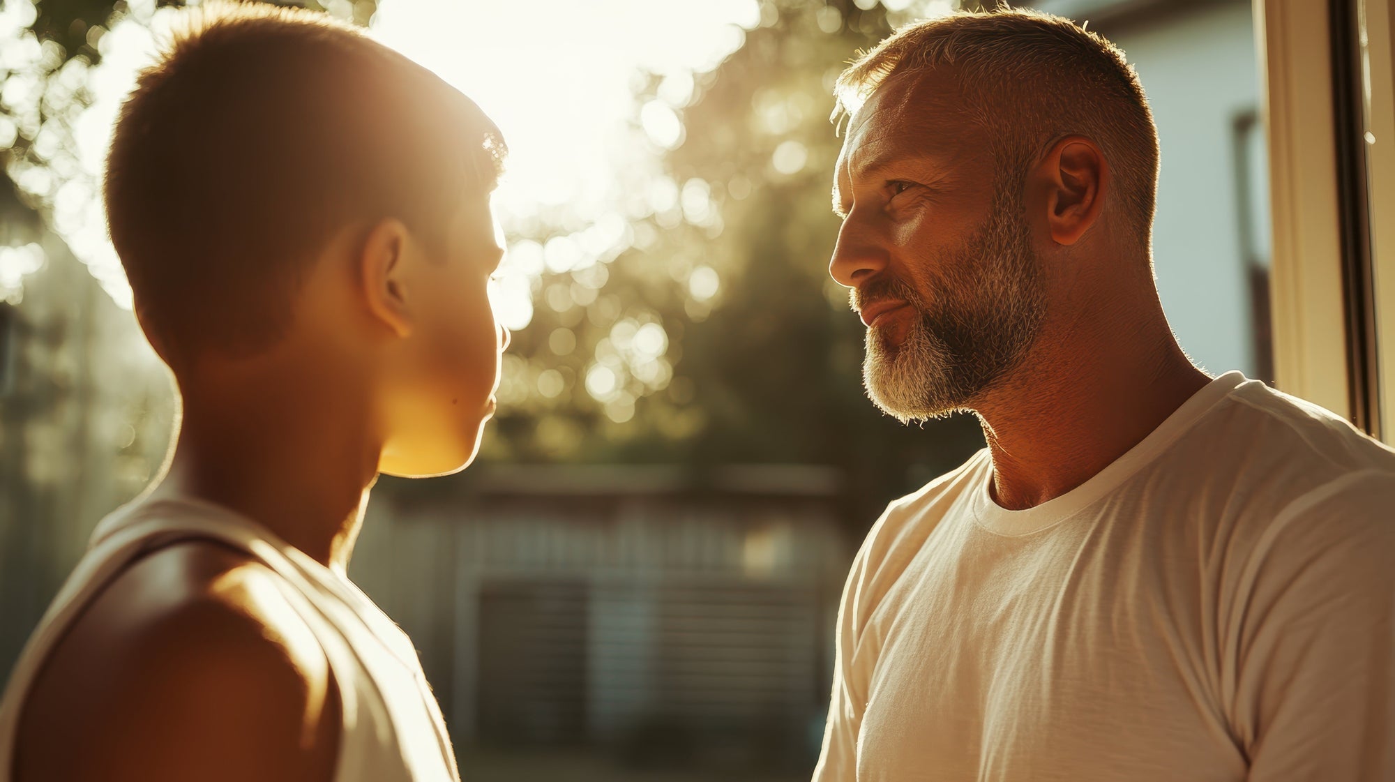 A father and son share a warm, sunlit moment, representing the genetic and emotional connection between generations, linked to childhood bedwetting.