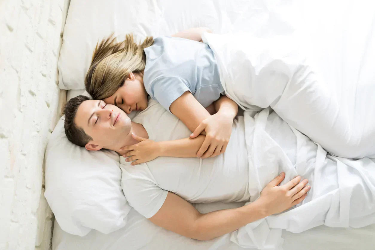 Well-rested parents sleeping peacefully after solving their child’s bedwetting with a bedwetting alarm.